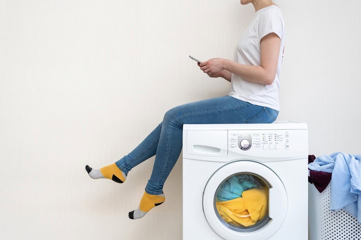 Person sitting on top of laundry machine.