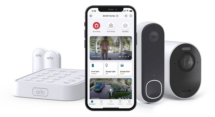 Arlo Secure 5 on cell phone with smart doorbell, smart camera, and security pad in background.