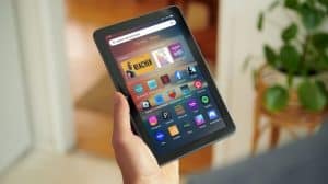 Amazon's new Fire HD 8 tablet model behind held, with various apps displayed.