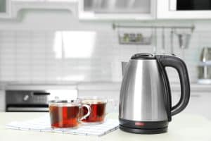 Electric kettle on a counter with cups of tea